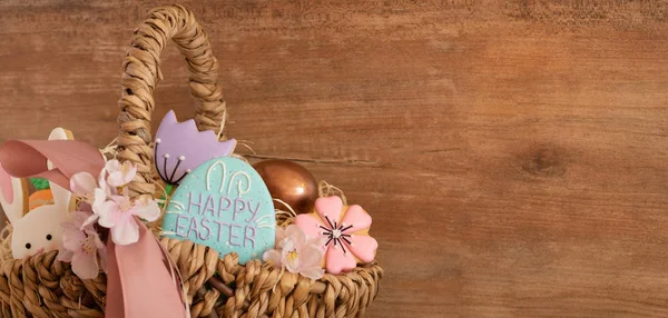 Frohe Ostern. mehrfarbige Pastell-Osterkekse in einem Weidenkorb auf Holz-Hintergrund — Stockfoto