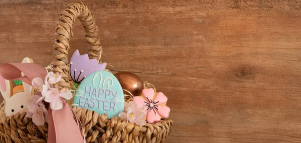 Feliz Pascua. Galletas de Pascua pastel multicolores en una canasta de mimbre sobre un fondo de madera — Foto de Stock