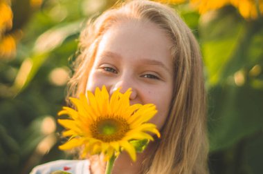 Ayçiçeği tarlasında güzel bir genç kadın. Güneşteki genç bir kadının portresi. Polen alerjisi kavramı.