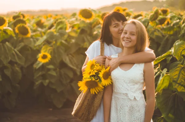 Gelukkige moeder en haar tienerdochter in het zonnebloemenveld. Buiten levensstijl geluk — Stockfoto