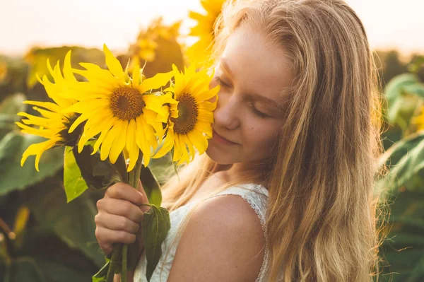 Schöne junge Frau in einem Sonnenblumenfeld. Porträt einer jungen Frau in der Sonne. Pollenallergien-Konzept. — Stockfoto