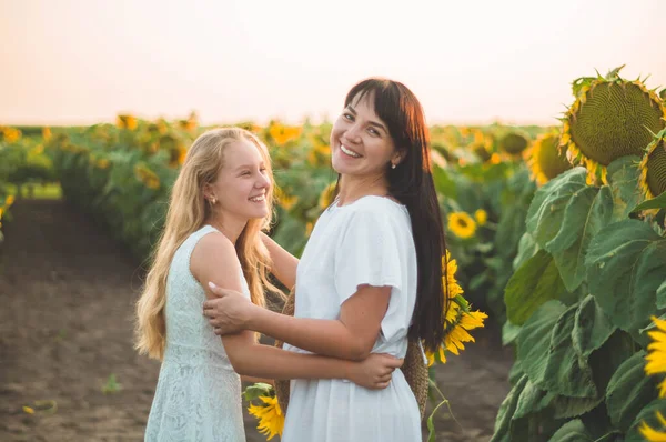 Gelukkige moeder en haar tienerdochter in het zonnebloemenveld. Buiten levensstijl geluk — Stockfoto