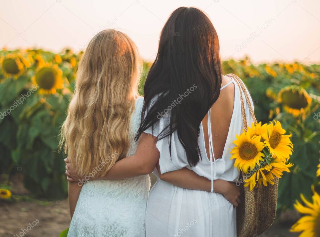 Happy mother and her teenager daughter in the sunflower field. Outdoors lifestyle happiness