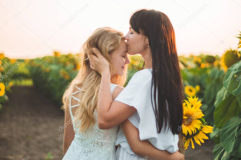 Happy mother and her teenager daughter in the sunflower field. Outdoors lifestyle happiness