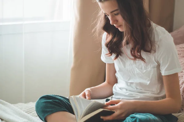 La adolescente cristiana tiene la Biblia en sus manos. Leyendo la Biblia en el salón. concepto de fe, espiritualidad y religión — Foto de Stock