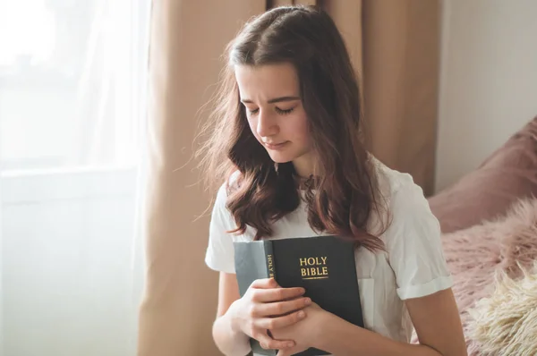 Gadis remaja Kristen memegang Alkitab di tangannya. Membaca Alkitab di ruang tamu. konsep untuk iman, spiritualitas dan agama — Stok Foto
