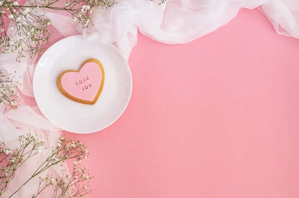 Twigs of gypsophila en koekjes met de inscriptie Love you on a pink background. Voorjaar achtergrond — Stockfoto