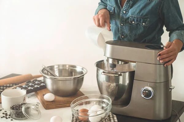 La chica pastelera con camisa de mezclilla está preparando un pastel. Concepto de ingredientes para cocinar productos harineros o postres . — Foto de Stock