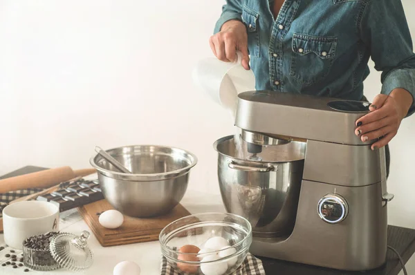 La pasticciera in camicia di jeans sta preparando una torta. Concetto ingredienti per la cottura di prodotti di farina o dessert . — Foto Stock