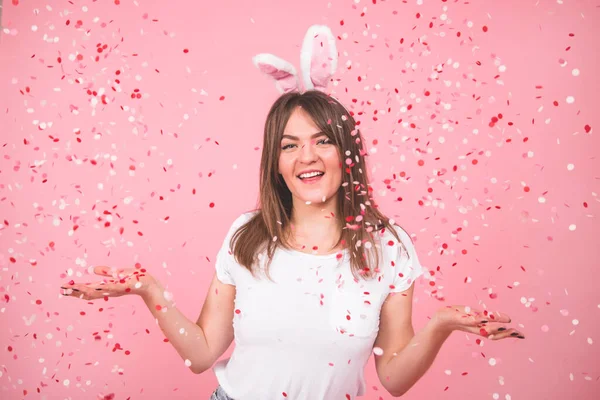 Konsep Liburan. Cantik tersenyum gadis memegang confetti di tangan Terisolasi di atas latar belakang merah muda — Stok Foto