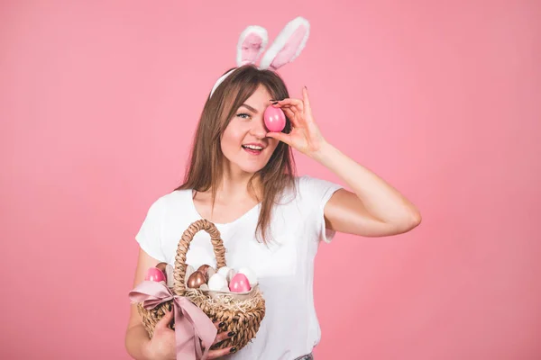 Selamat Paskah. Potret seorang gadis cantik dengan keranjang telur Paskah berdiri terisolasi atas latar belakang merah muda. Emosi — Stok Foto