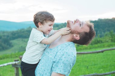 Sevgi dolu bir aile. Baba ve oğlu dışarıda oynayıp sarılıyorlar.. 