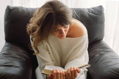 Güzel genç bayan evde bir kitap okuyor. Önemli bir kitap okuyan düşünceli bir kız.