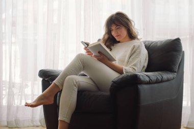 Güzel genç bayan evde bir kitap okuyor. Önemli bir kitap okuyan düşünceli bir kız.