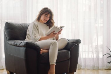 Güzel genç bayan evde bir kitap okuyor. Önemli bir kitap okuyan düşünceli bir kız.