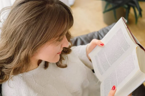 Güzel genç bayan evde bir kitap okuyor. Önemli bir kitap okuyan düşünceli bir kız. — Stok fotoğraf