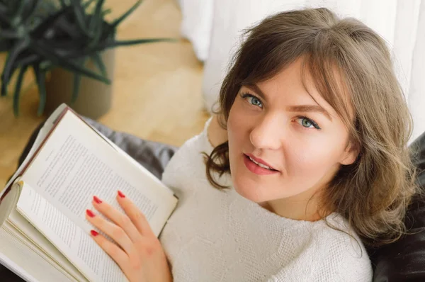 Güzel genç bayan evde bir kitap okuyor. Önemli bir kitap okuyan düşünceli bir kız. — Stok fotoğraf