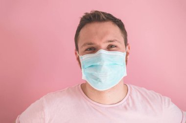 Pembe arka planda viral maskeli bir adam. Koronavirüsü önlemek için yüz koruması takıyor.