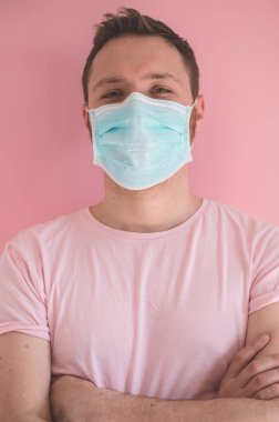Pembe arka planda viral maskeli bir adam. Koronavirüsü önlemek için yüz koruması takıyor.