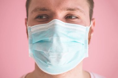 Pembe arka planda viral maskeli bir adam. Koronavirüsü önlemek için yüz koruması takıyor.