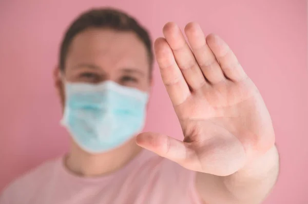 Mężczyzna w masce wirusowej na różowym tle, noszący ochronę twarzy w zapobieganiu koronawirusowi — Zdjęcie stockowe