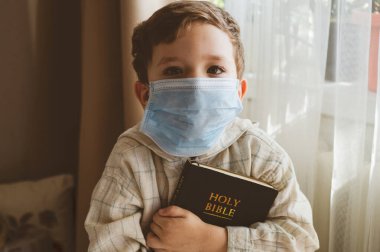 Coronavirus covid-19. Çocuğun elinde bir İncil var. İncil okumaları ve dualar. Barış, umut kavramı