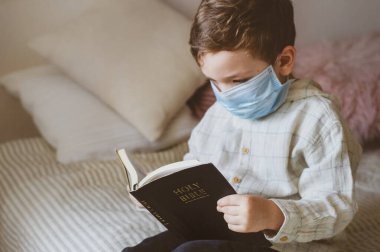 Coronavirus covid-19. Çocuğun elinde bir İncil var. İncil okumaları ve dualar. Barış, umut kavramı