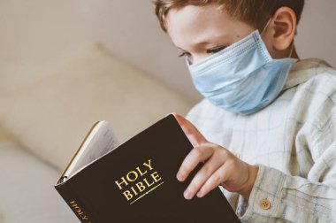 Coronavirus covid-19. Çocuğun elinde bir İncil var. İncil okumaları ve dualar. Barış, umut kavramı