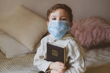 Coronavirus covid-19. Çocuğun elinde bir İncil var. İncil okumaları ve dualar. Barış, umut kavramı