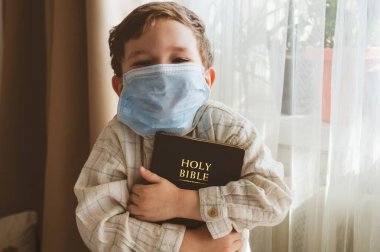 Coronavirus covid-19. Çocuğun elinde bir İncil var. İncil okumaları ve dualar. Barış, umut kavramı