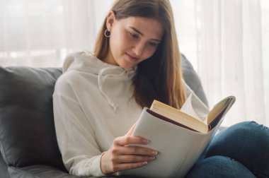 Okuma ve geliştirme. Güzel genç bayan evde bir kitap okuyor. Önemli bir kitap okuyan düşünceli bir kız.