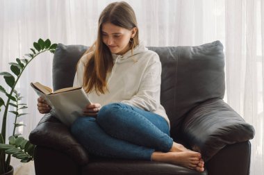 Okuma ve geliştirme. Güzel genç bayan evde bir kitap okuyor. Önemli bir kitap okuyan düşünceli bir kız.