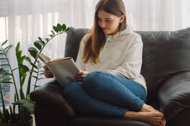 Okuma ve geliştirme. Güzel genç bayan evde bir kitap okuyor. Önemli bir kitap okuyan düşünceli bir kız.