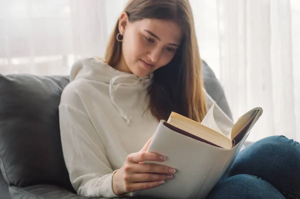 Membaca dan mengembangkan. Wanita muda yang cantik membaca buku di rumah. Gadis bijaksana membaca buku penting — Stok Foto