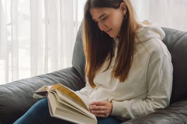 Okuma ve geliştirme. Güzel genç bayan evde bir kitap okuyor. Önemli bir kitap okuyan düşünceli bir kız. — Stok fotoğraf