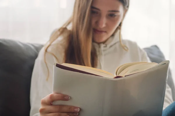 Membaca dan mengembangkan. Wanita muda yang cantik membaca buku di rumah. Gadis bijaksana membaca buku penting — Stok Foto