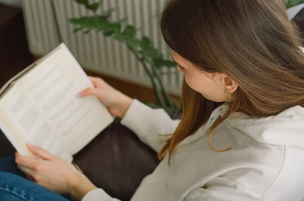 Leitura e desenvolvimento. Beleza jovem está lendo um livro em casa. Menina pensativa lendo livro importante — Fotografia de Stock