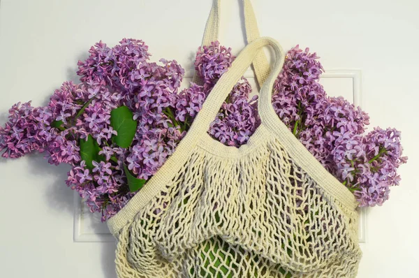 Blooming spring lilac flowers in string bag. Spring background — Stock Photo, Image