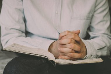 İncil 'i okuyorum. Dua et. Elleri dua konseptinde birleştirilmiş. İnanç kavramı