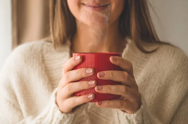 Žena s pohárem horkého nápoje u okna. Dobré ráno s čajem. Podzimní zimní zimní čas. — Stock fotografie