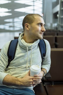 Kahve ile yolcu elinde fincan ve H oturan sırt çantası