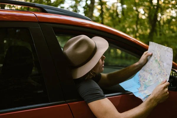 Voyageur homme avec chapeau regarder la carte près de la voiture en forêt d'automne — Photo