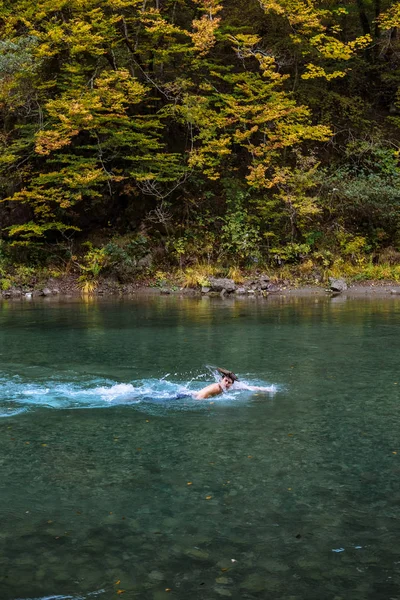 Young sports man bathing in a mountain lake in the fall — Stock Photo, Image