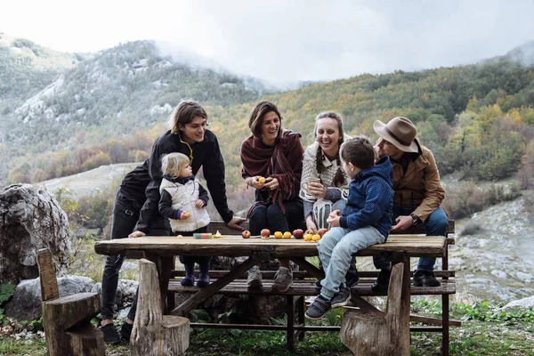 Ami joyeux avec des enfants près de la table contre les montagnes dans un — Photo