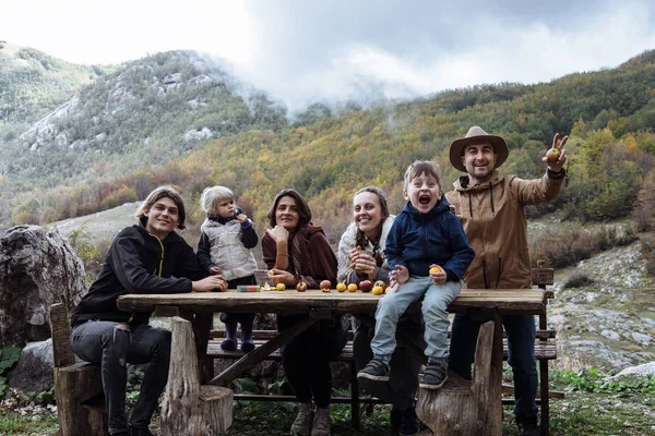 Ami joyeux avec des enfants près de la table contre les montagnes dans un — Photo