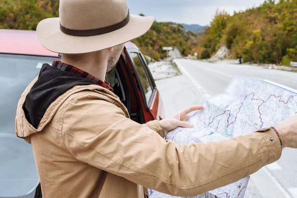 Bel homme avec la carte en main debout à côté d'une voiture à Mont — Photo