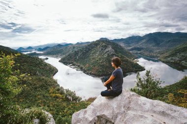 Cliff'in kenarında oturan ve için güzel görünümlü genç kadın vie