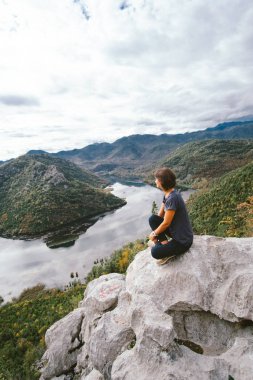 Cliff'in kenarında oturan ve için güzel görünümlü genç kadın vie