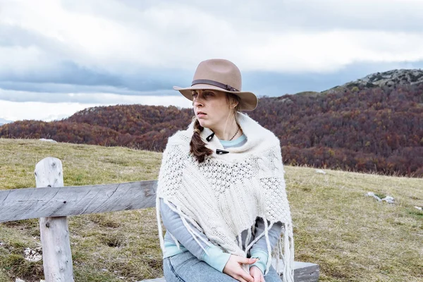 Genç kadın bir şapka ve sonbahar dağlar Durmit zevk panço — Stok fotoğraf