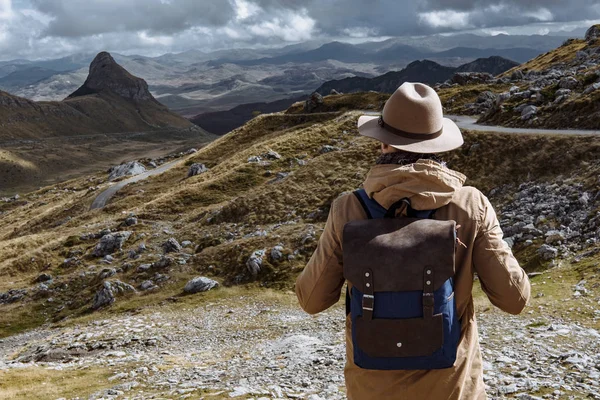 Homme voyageur avec chapeau et sac à dos regardant en haut de la colline, D — Photo